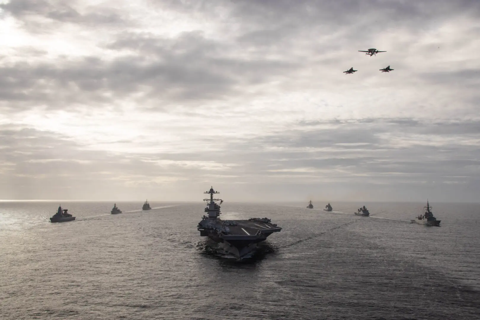 ATLANTIC OCEAN (Oct. 25, 2022) Aircraft attached to Carrier Air Wing (CVW) 8 fly over the first-in-class aircraft carrier USS Gerald R. Ford (CVN 78) as the ship steams in formation in the Atlantic Ocean with the Spanish Armada frigate çlvaro de Bazn (F 101), Danish navy frigate HDMS Peter Willemoes (F362), Dutch navy frigate HNLMS De Zeven Provincien (F 802), the U.S. Navy Arleigh Burke-class guided-missile destroyer USS Ramage (DDG 61), German navy frigate FGS Hessen (F 221), Dutch navy frigate HNLMS Van Amstel (F 831), and the U.S. Navy Ticonderoga-class guided-missile cruiser USS Normandy (CG 60), Oct. 25, 2022. The Gerald R. Ford Carrier Strike Group (GRFCSG) is deployed in the Atlantic Ocean, conducting training and operations alongside NATO Allies and partners to enhance integration for future operations and demonstrate the U.S. NavyÕs commitment to a peaceful, stable and conflict-free Atlantic region. (U.S. Navy photo by Mass Communication Specialist 2nd Class Jackson Adkins)